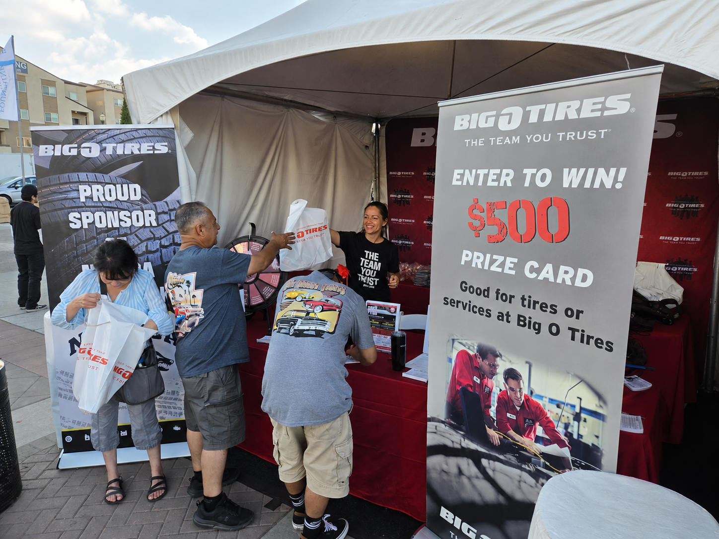 Promotional staff engaging attendees at a Big O Tires outdoor event booth
